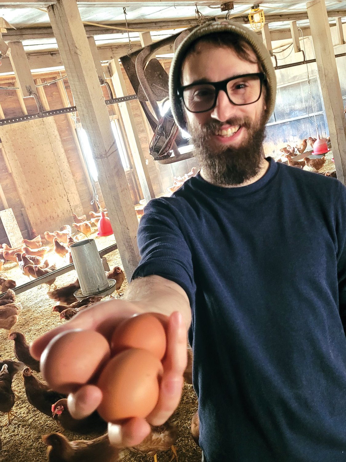 EGGING ON THE COMPETITION: Fourth-generation poultry farmer Adam Baffoni, of Baffoni Poultry Farm in Johnston, holds three fresh eggs laid by a few of his nearly 8,000 egg-laying Rhode Island Red hens. (Sun Rise photos by Rory Schuler)